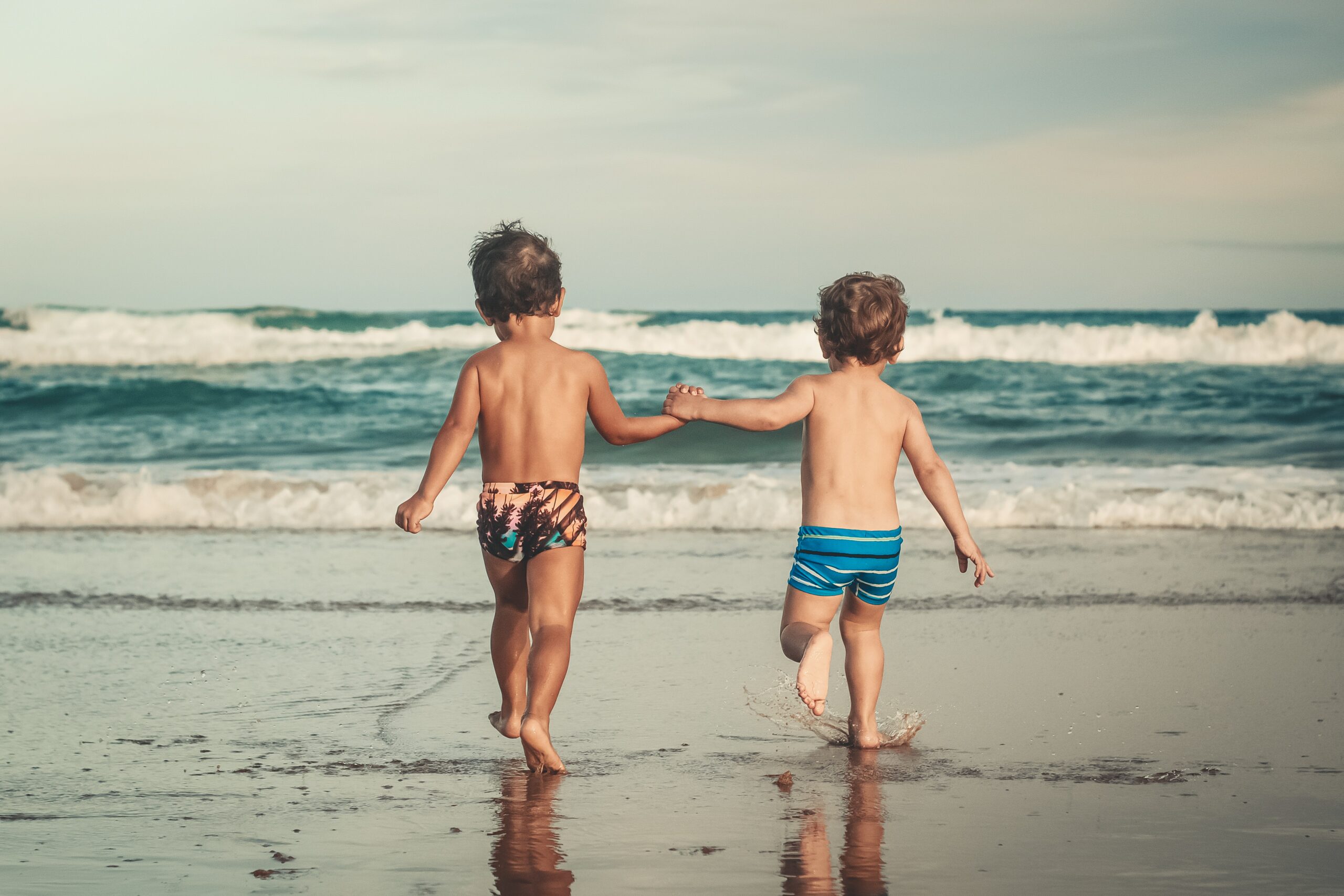 dois meninos de mãos dadas em frente ao mar