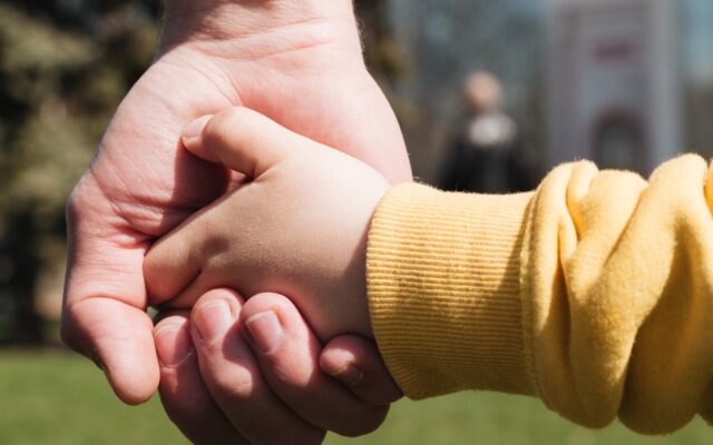 maõs de um adulto segurando as mãos de uma criança pequena
